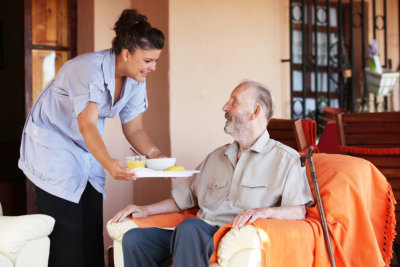 caregiver providing meal to old man