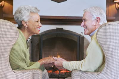 couple sitting in living room by fireplace holding hands